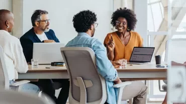Group of diverse colleagues having a discussion around a conference table.